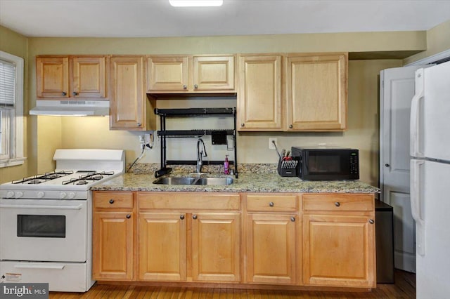 kitchen featuring white appliances, a sink, under cabinet range hood, light stone countertops, and light brown cabinetry