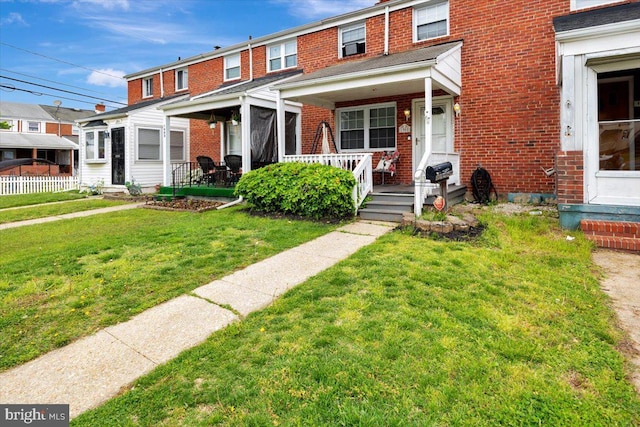 view of property featuring brick siding, a front lawn, and covered porch
