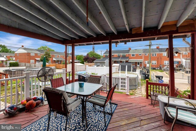 deck with a residential view, outdoor dining space, a fenced backyard, and a shed