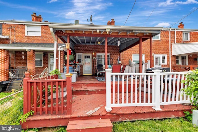 rear view of house with brick siding, a chimney, and a deck
