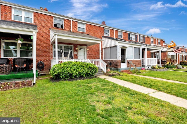 townhome / multi-family property with brick siding, a front yard, and a chimney