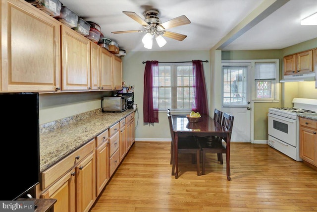 kitchen featuring white gas range, under cabinet range hood, light wood-style floors, and healthy amount of natural light