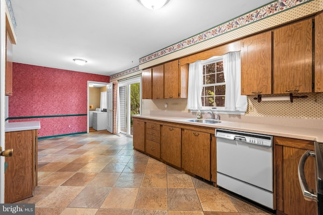 kitchen featuring white dishwasher, wallpapered walls, brown cabinetry, light countertops, and stone tile flooring