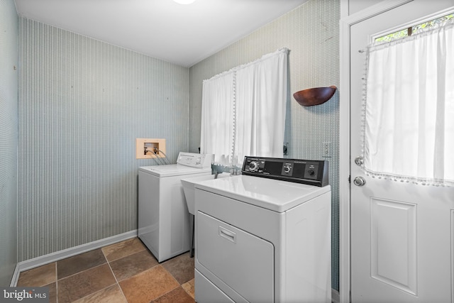 clothes washing area featuring washer and dryer, stone finish floors, baseboards, and wallpapered walls