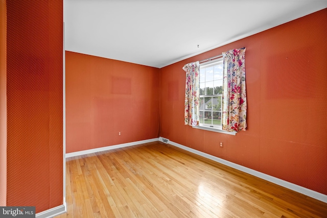 empty room featuring wood finished floors and baseboards