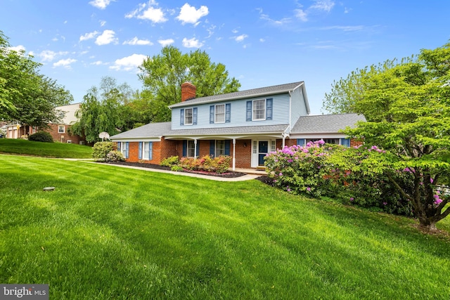 view of front facade featuring a chimney, a front lawn, a porch, and brick siding