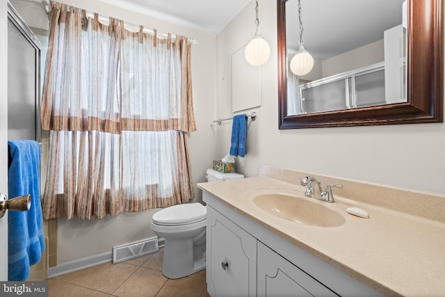 bathroom featuring tile patterned flooring, vanity, toilet, and a shower