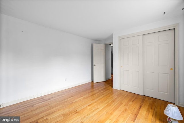 unfurnished bedroom with wood finished floors, a closet, and baseboards