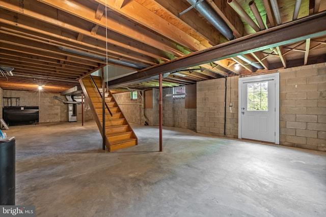 below grade area featuring stairway and concrete block wall
