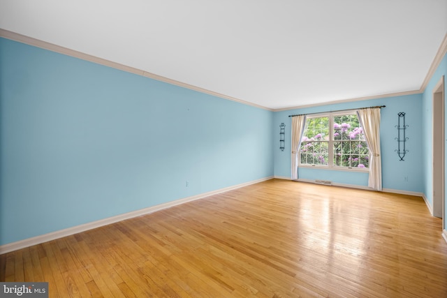 empty room with ornamental molding, light wood-style flooring, and baseboards