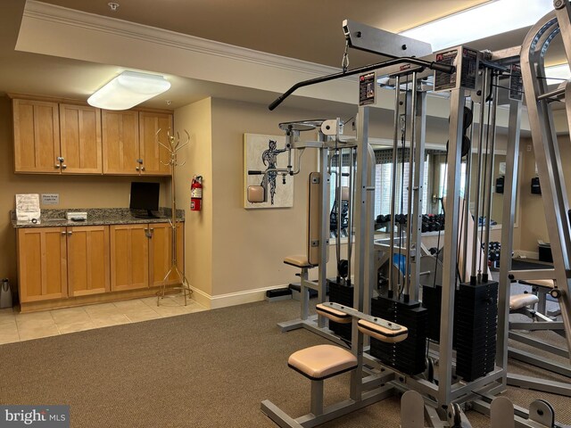 exercise room featuring baseboards, ornamental molding, and light tile patterned floors