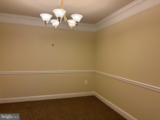 empty room featuring a chandelier, dark colored carpet, ornamental molding, and baseboards