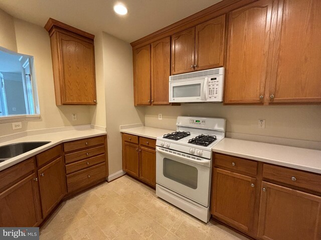 kitchen with white appliances, brown cabinets, light countertops, and recessed lighting