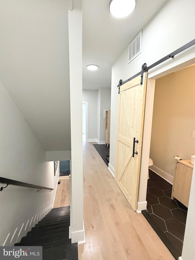hall with a barn door, wood finished floors, and baseboards