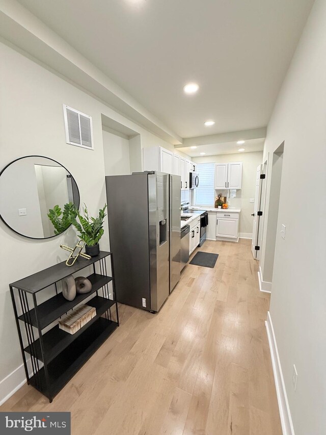 kitchen featuring stainless steel appliances, white cabinetry, light countertops, light wood-style flooring, and recessed lighting