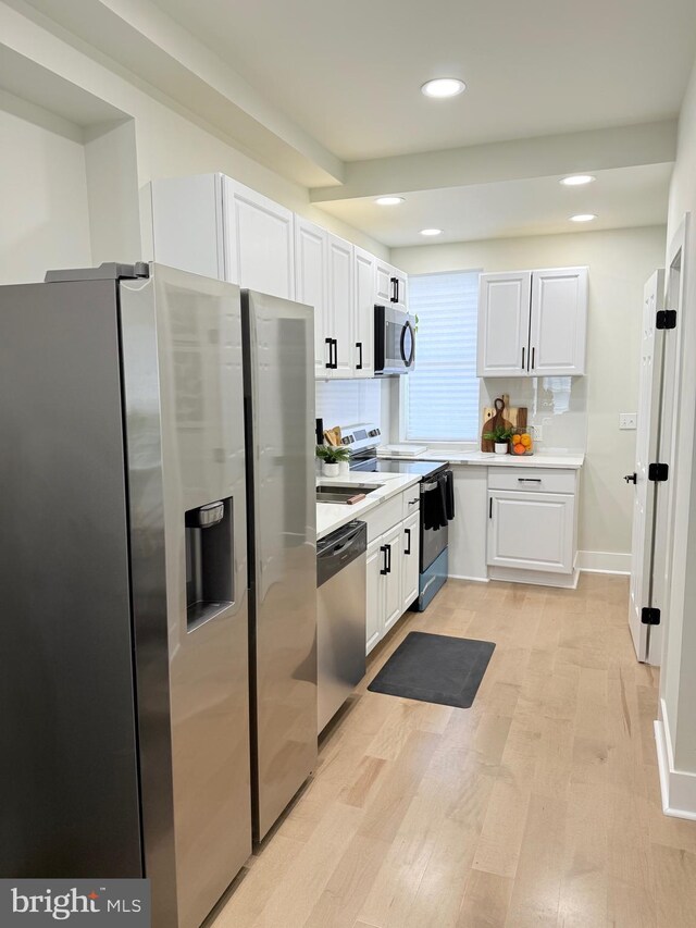 kitchen with appliances with stainless steel finishes, light countertops, white cabinetry, light wood-style flooring, and recessed lighting
