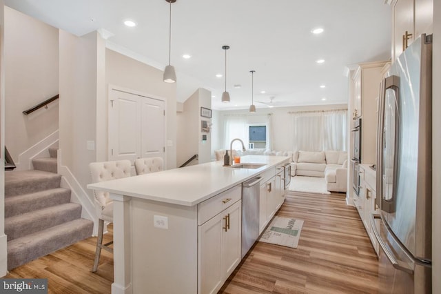 5753 Frederick Douglas Pl, White Plains, MD 20695 - kitchen with stainless steel appliances, open floor plan, a sink, a kitchen bar, and light countertops