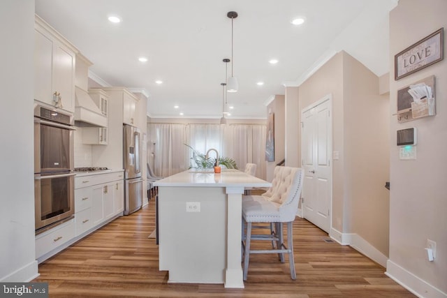 5753 Frederick Douglas Pl, White Plains, MD 20695 - kitchen with stainless steel appliances, a kitchen bar, baseboards, ornamental molding, and an island with sink