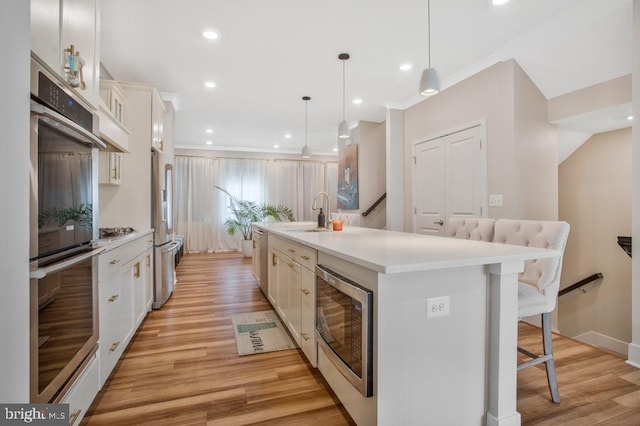 5753 Frederick Douglas Pl, White Plains, MD 20695 - kitchen featuring stainless steel appliances, a sink, a kitchen breakfast bar, an island with sink, and light wood-style flooring