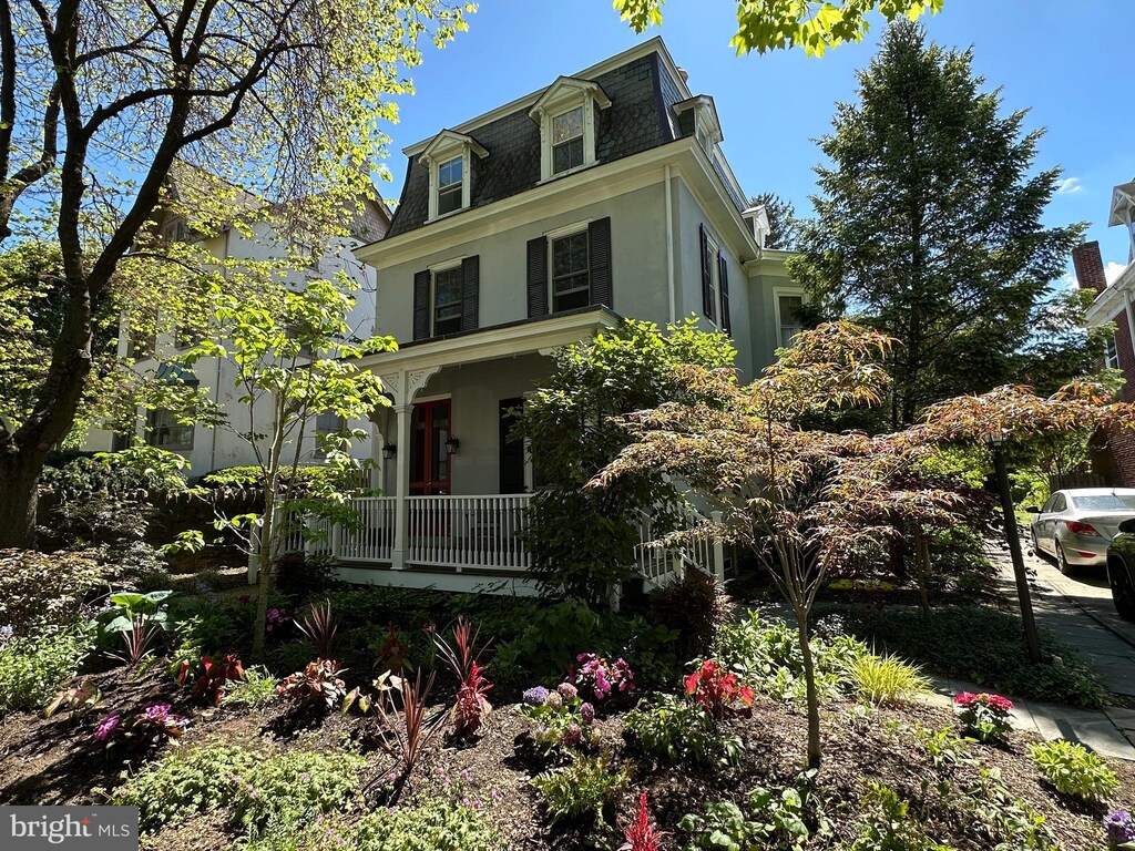 second empire-style home featuring mansard roof, stucco siding, and covered porch