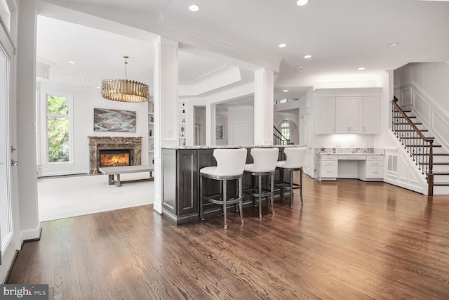 7845 Montvale Way, Mclean, VA 22102 - kitchen featuring a glass covered fireplace, white cabinetry, a kitchen breakfast bar, crown molding, and dark wood-type flooring