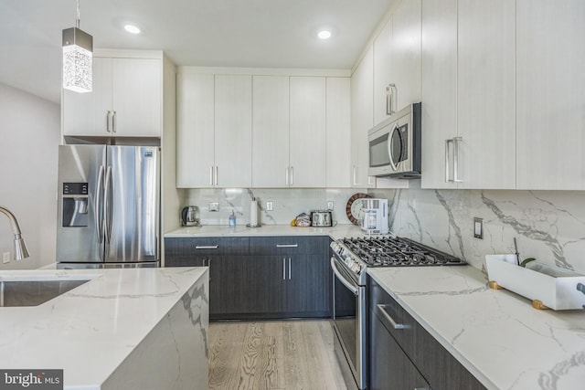 2812 Georgia Ave NW Unit 6, Washington, DC 20001 - kitchen featuring appliances with stainless steel finishes, a sink, light wood-style flooring, decorative light fixtures, and backsplash