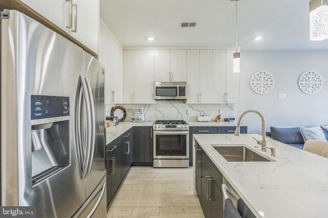 2812 Georgia Ave NW Unit 6, Washington, DC 20001 - kitchen featuring appliances with stainless steel finishes, a sink, light wood-type flooring, pendant lighting, and decorative backsplash