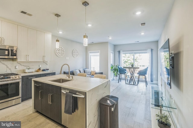 2812 Georgia Ave NW Unit 6, Washington, DC 20001 - kitchen featuring stainless steel appliances, a sink, open floor plan, light wood-style floors, and a kitchen island with sink