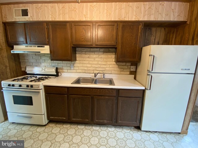 kitchen featuring white appliances, under cabinet range hood, a sink, and light countertops