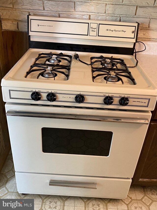 kitchen view of white range with gas stovetop and wooden walls