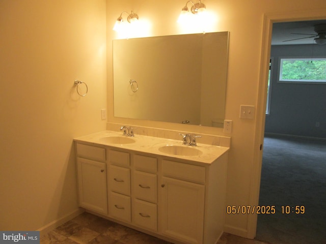 full bath with double vanity, ceiling fan, and baseboards