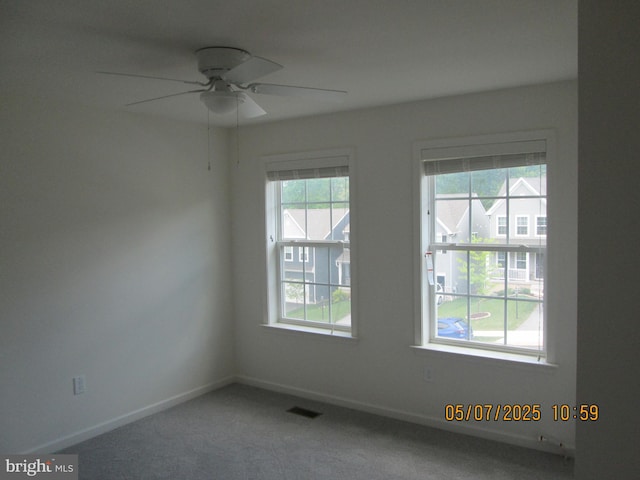carpeted spare room featuring ceiling fan and baseboards