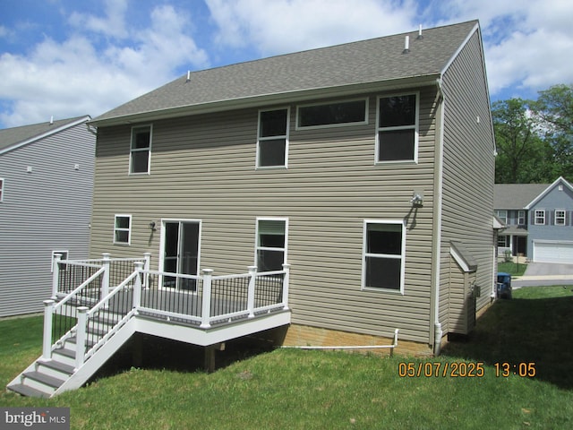 rear view of property with a deck, a lawn, and a shingled roof