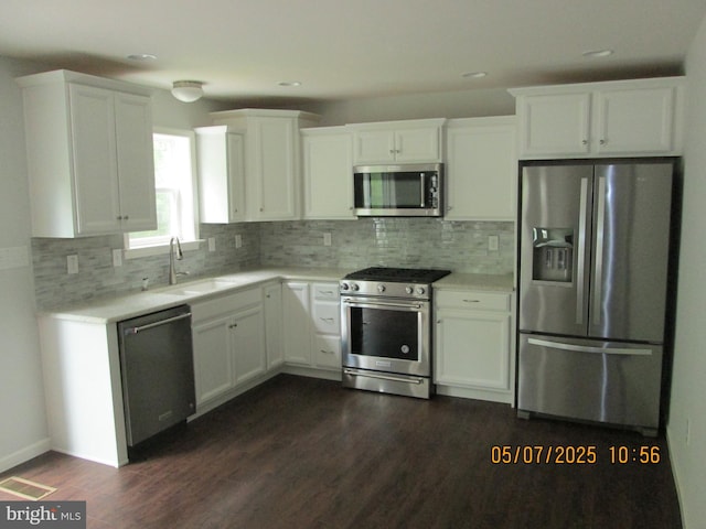 kitchen featuring stainless steel appliances, a sink, white cabinets, light countertops, and tasteful backsplash