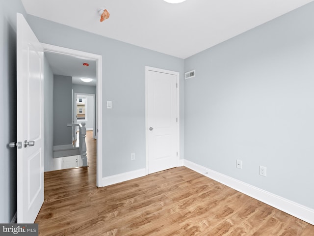 unfurnished bedroom featuring wood finished floors, baseboards, and a closet