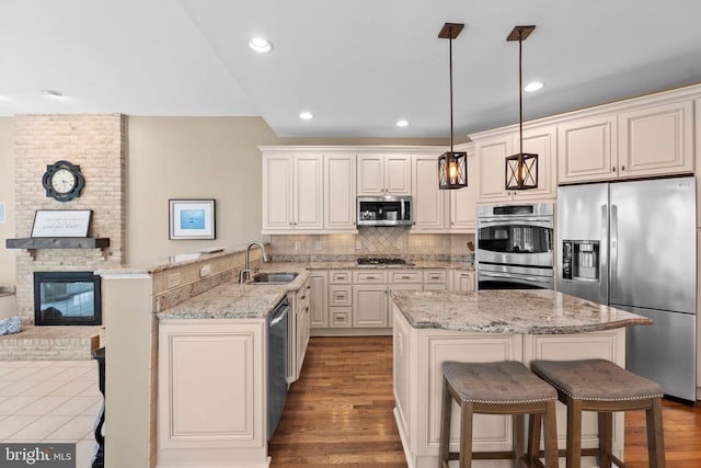 kitchen with appliances with stainless steel finishes, a sink, a breakfast bar, a peninsula, and recessed lighting