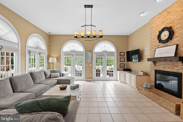 living room featuring healthy amount of natural light, a brick fireplace, light tile patterned floors, and a chandelier