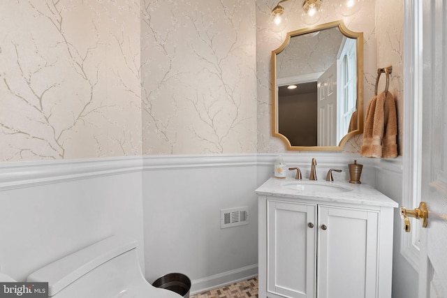 bathroom featuring vanity, wainscoting, and toilet