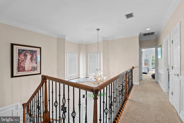 corridor with a chandelier, carpet, ornamental molding, an upstairs landing, and a decorative wall
