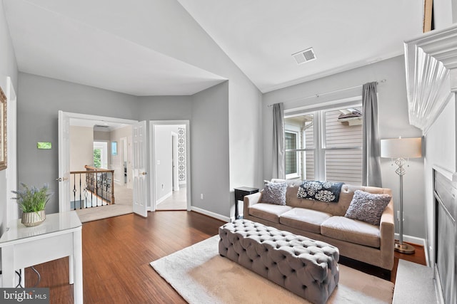living area featuring wood finished floors, baseboards, and lofted ceiling