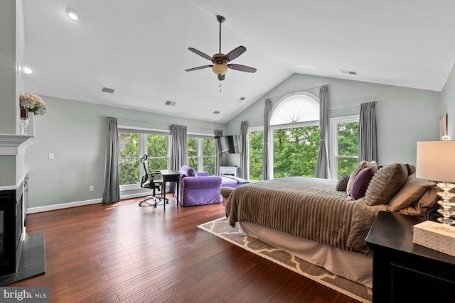 bedroom with multiple windows, a glass covered fireplace, dark wood-style floors, baseboards, and high vaulted ceiling