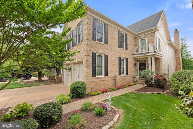 view of front facade featuring brick siding, driveway, a front lawn, a balcony, and a chimney