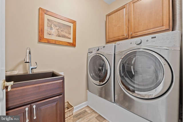 laundry area featuring cabinet space, washing machine and dryer, light wood-style floors, and baseboards