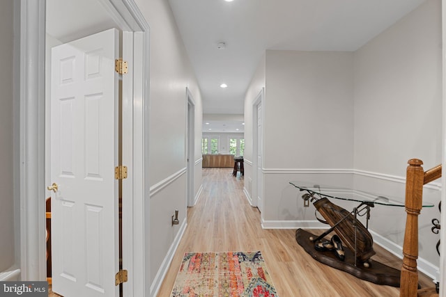 hall featuring light wood finished floors, recessed lighting, and baseboards