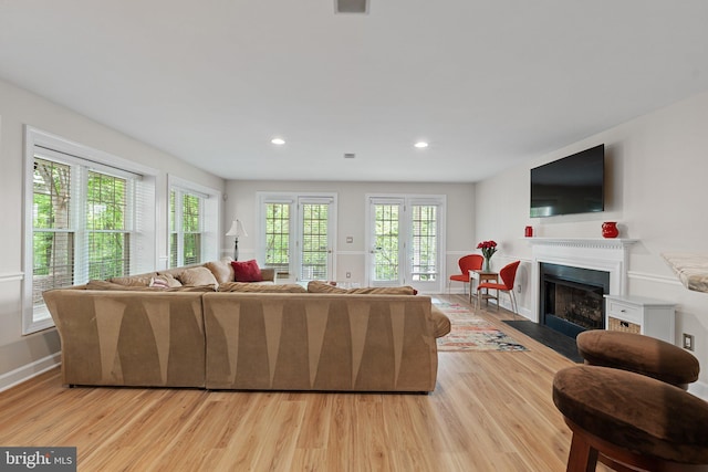 living room featuring light wood-type flooring, a fireplace with flush hearth, recessed lighting, and baseboards