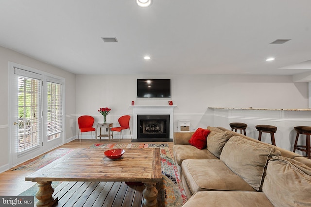 living room with wood finished floors, a fireplace with flush hearth, recessed lighting, and baseboards