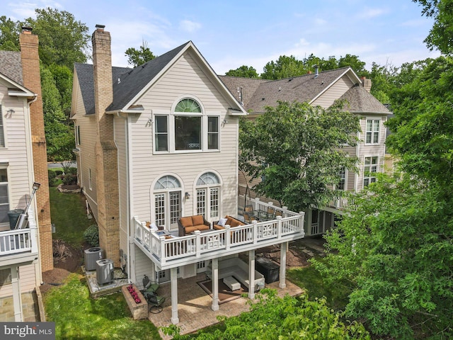 rear view of house featuring central air condition unit, a deck, a chimney, and outdoor lounge area