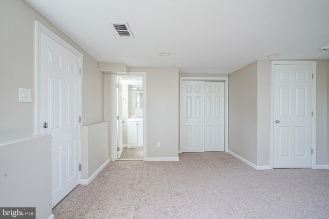 unfurnished bedroom featuring carpet floors, baseboards, a closet, and ensuite bath
