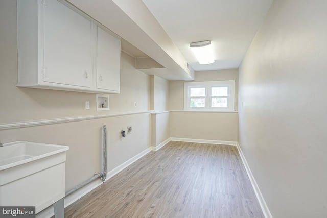 washroom featuring hookup for a gas dryer, cabinet space, light wood finished floors, washer hookup, and baseboards