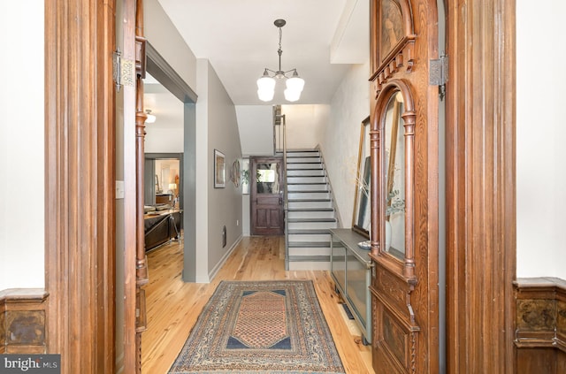entrance foyer featuring light wood-type flooring, stairway, and a chandelier